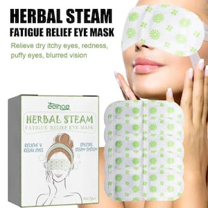 Puede incluir: Una máscara de ojos de vapor herbal blanca con un patrón floral verde. La caja del empaque presenta el texto "HERBAL STEAM FATIGUE RELIEF EYE MASK", "RELIEVE & RELAX EYES" y "SPECIAL STEAM SYSTEM", junto con la ilustración de una persona.