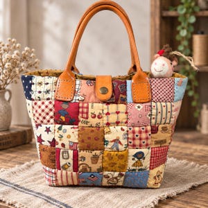 May include: A patchwork tote bag featuring a variety of colourful fabric squares with patterns including stars, hearts, apples, and cartoon figures. The bag has two tan leather handles and a central leather tab closure with a brass-coloured snap button.