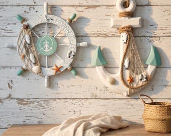 May include: A white ship wheel with teal accents and a white anchor with teal tips, both decorated with fishing nets, small white fish, seashells, a starfish, and a life ring. The ship wheel features a central teal circle with an anchor icon.