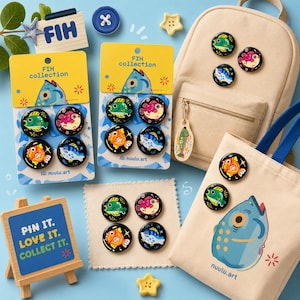 May include: A collection of circular pins featuring colorful fish illustrations, displayed on yellow and blue backing cards. The set includes a beige canvas backpack and a tote bag adorned with these fish pins, alongside a small wooden easel sign.