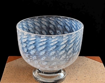 May include: A clear glass bowl with a rounded shape and a short pedestal base, featuring a swirling pattern of white and blue oval-shaped inclusions embedded within the glass walls, creating a textured appearance throughout the entire vessel.