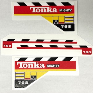 May include: Three white stickers with black and red stripes. The stickers have the text "Tonka Mighty" and the number "768" printed on them.