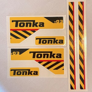 May include: Four yellow and black warning stickers with the word "Tonka" printed in black. The stickers have a red stripe and the text "T.O.E." printed in black.
