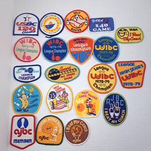 May include: A collection of twenty-two embroidered bowling patches in various shapes and colors, featuring text such as USBC 120 Game, WIBC League Champion, YABA I Beat My Coach, and High Game Award, with illustrations of bowling pins, balls, and clowns.