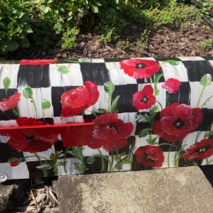 May include: A white and black checkered mailbox with a red flag and painted red poppy flowers.
