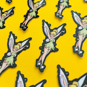 May include: Multiple die-cut stickers featuring a cartoon fairy with blonde hair in a bun, wearing a light green dress and translucent iridescent wings. The fairy is depicted in various flying poses surrounded by small white star-shaped sparkles.