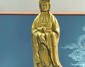 Statua di Guan Yin in piedi con loto, rosario e veste fluente in rilievo.