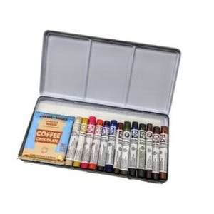 May include: A rectangular silver metal tin containing a row of twelve cylindrical oil pastels in various colors and a small rectangular packet labeled Coffee Chocolate. The tin has an open hinged lid and a white interior tray holding the art supplies.