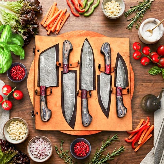 A 5-piece Damascus steel chef knife set with hand-forged layered blade patterns and wooden handles — functional kitchen art that looks as good on display as it does in use.
