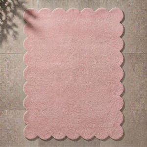 Soft pink cloud rug with a scalloped edge and plush surface, designed for cozy contemporary interiors. This wavy border area carpet brings a gentle decorative touch to nurseries, children's bedrooms, living rooms, and relaxing reading spaces. Pair it with white furniture, pastel cushions, natural wood, soft blankets, and minimalist accessories. The cloud-like silhouette creates visual interest while maintaining a calm, welcoming atmosphere suited to Scandinavian and modern decor.