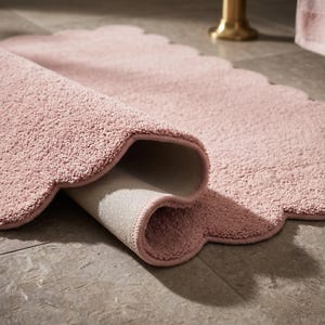 Pink cloud-shaped area rug with a scalloped outline and soft plush styling for inviting home interiors. Designed as a decorative floor mat, it adds charm to nursery spaces, children's bedrooms, cozy living rooms, and reading corners. The pastel pink palette works naturally with cream furniture, light oak finishes, white walls, and neutral textiles. Use this wavy border carpet to create a gentle focal point in modern Scandinavian-inspired decor.