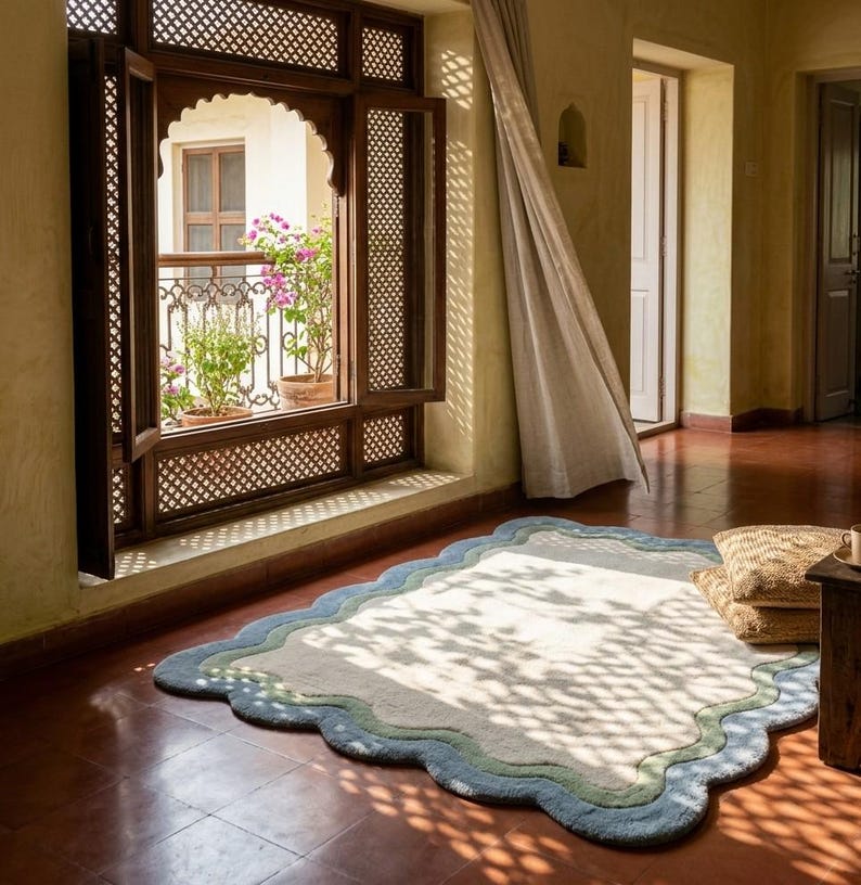 Scalloped area rug with wavy border placed near an arched wooden doorway on terracotta tiled flooring