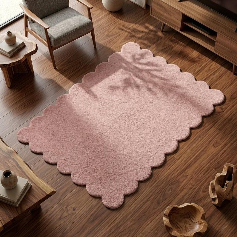 Scalloped border pink carpet featuring a cloud-inspired design for modern nursery and bedroom decor. Its plush-looking surface and rounded edges create a soft visual effect that complements cozy interiors. Suitable for children's rooms, reading nooks, living rooms, and relaxation areas, this decorative rug pairs well with pastel cushions, wooden furniture, cream bedding, and minimalist accessories. The organic shape brings personality to Scandinavian and contemporary spaces.