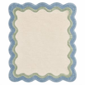 Top view close-up of scalloped area rug showing detailed blue wavy border stitching on cream tufted background