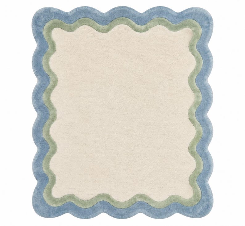 Top view close-up of scalloped area rug showing detailed blue wavy border stitching on cream tufted background