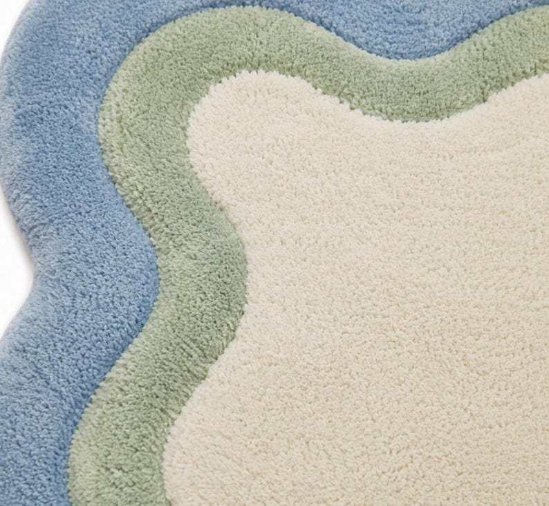 Top view of scalloped wavy edge rug showing sage green border pattern on cream textured base