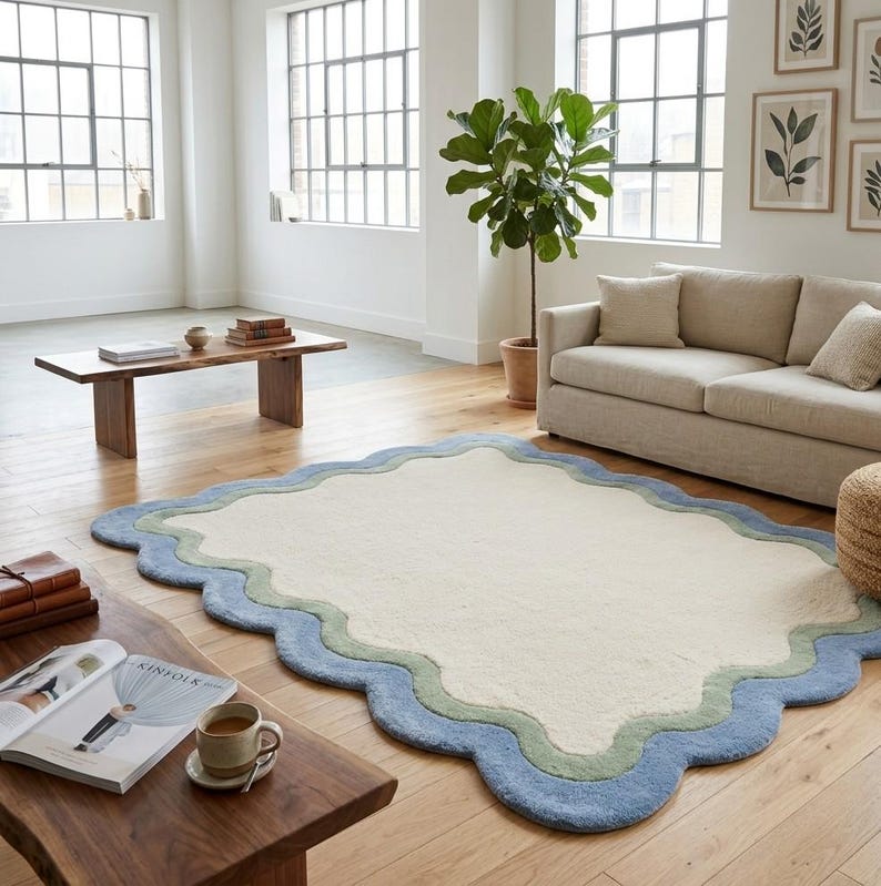 Scalloped area rug with wavy border placed in a living room near a potted plant and neutral toned sofa