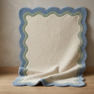 Close-up of scalloped rug corner showing blue wavy border detail against a white curtain background