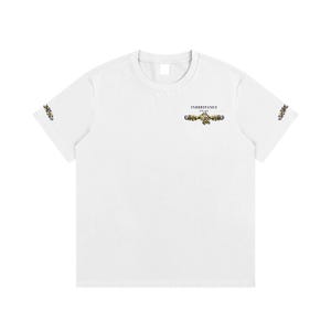 May include: A white short-sleeve t-shirt featuring a small graphic on the upper chest with the text INHERITANCE and EST 2024 above a gold and black ornate scrollwork design. Similar gold and black scrollwork patterns appear on both sleeves.