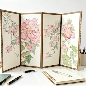 Peut inclure: Un paravent pliant à quatre panneaux présentant des illustrations à l'aquarelle de pivoines roses et de feuillage vert sur fond crème. Les panneaux sont encadrés d'une fine bordure brune, affichant un art botanique détaillé.