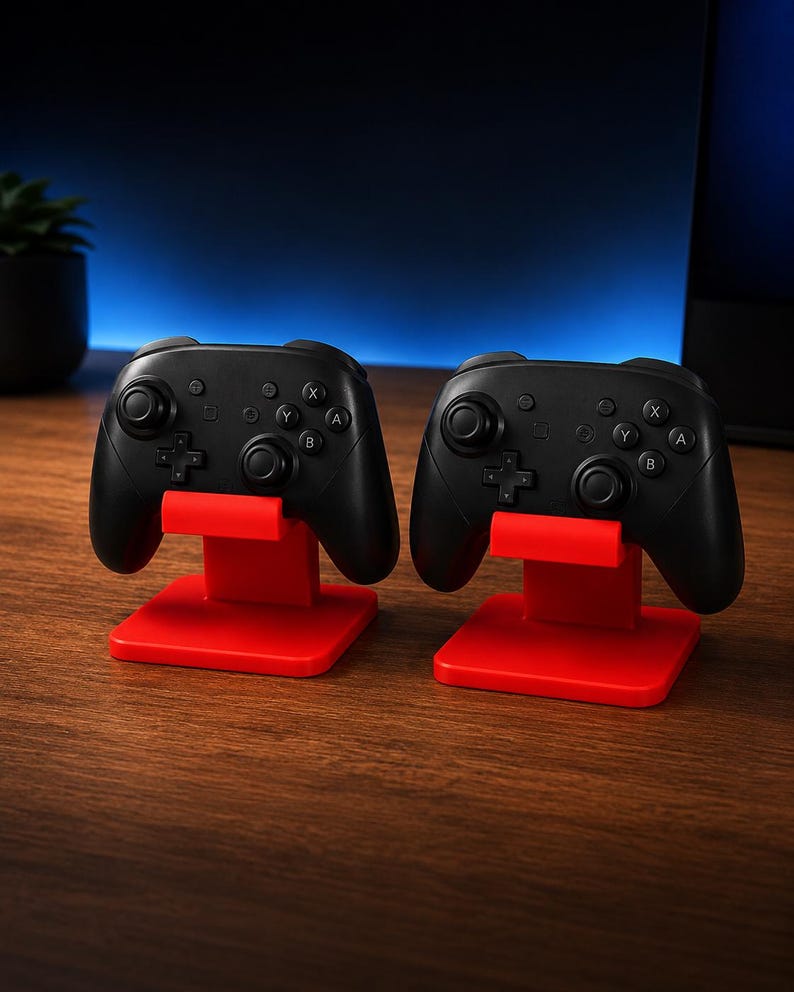 May include: Two black wireless game controllers, each resting on a bright red plastic stand. The controllers feature dual analog sticks, a directional pad, and four action buttons labeled A, B, X, and Y, along with several small system buttons.