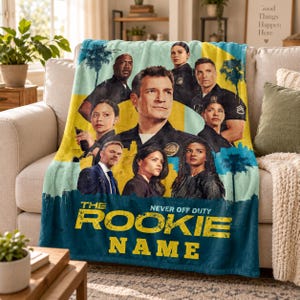 May include: A soft fleece throw blanket featuring a collage of characters from the television show The Rookie. The design includes a yellow and blue color scheme with palm tree silhouettes and the text THE ROOKIE NEVER OFF DUTY NAME.