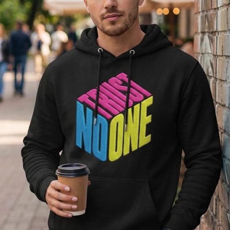 May include: A black hooded sweatshirt featuring a graphic of a three-dimensional cube with the text TRUST NO ONE printed on its sides. The top of the cube is pink, the left side is blue, and the right side is yellow. The hoodie has a front pocket.