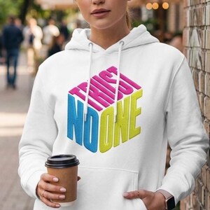 May include: A white hooded sweatshirt featuring a graphic of a three-dimensional cube with the text TRUST NO ONE printed on its faces. The text is rendered in pink, blue, and yellow, and the hoodie includes a front kangaroo pocket and drawstrings.