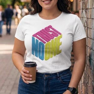 May include: A white short-sleeve t-shirt featuring a graphic design of a three-dimensional cube. The text "TRUST NO ONE" is printed on the cube faces in pink, blue, and yellow, creating a geometric visual effect on the front of the garment.