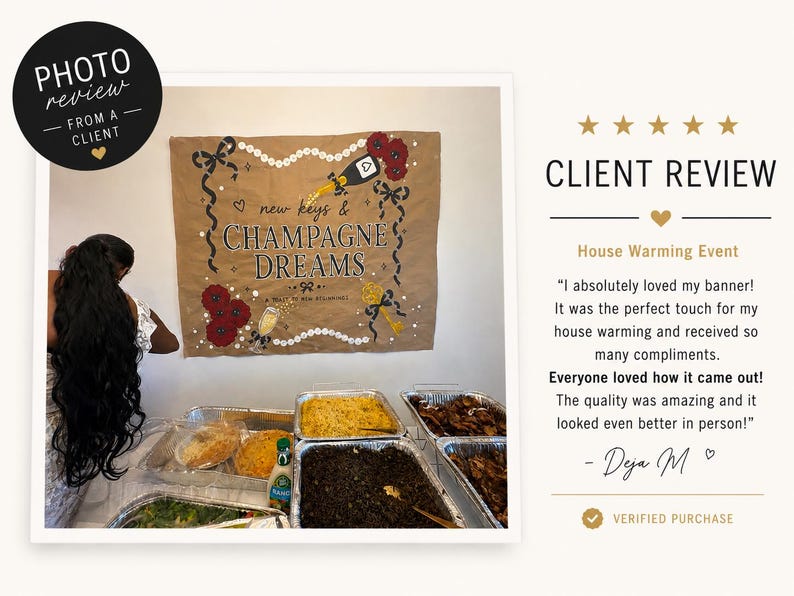 May include: A tan fabric banner featuring the text "new keys & CHAMPAGNE DREAMS" and "A TOAST TO NEW BEGINNINGS". The design includes illustrations of a champagne bottle, red flowers, a gold key, and black ribbons, displayed above a table of food.