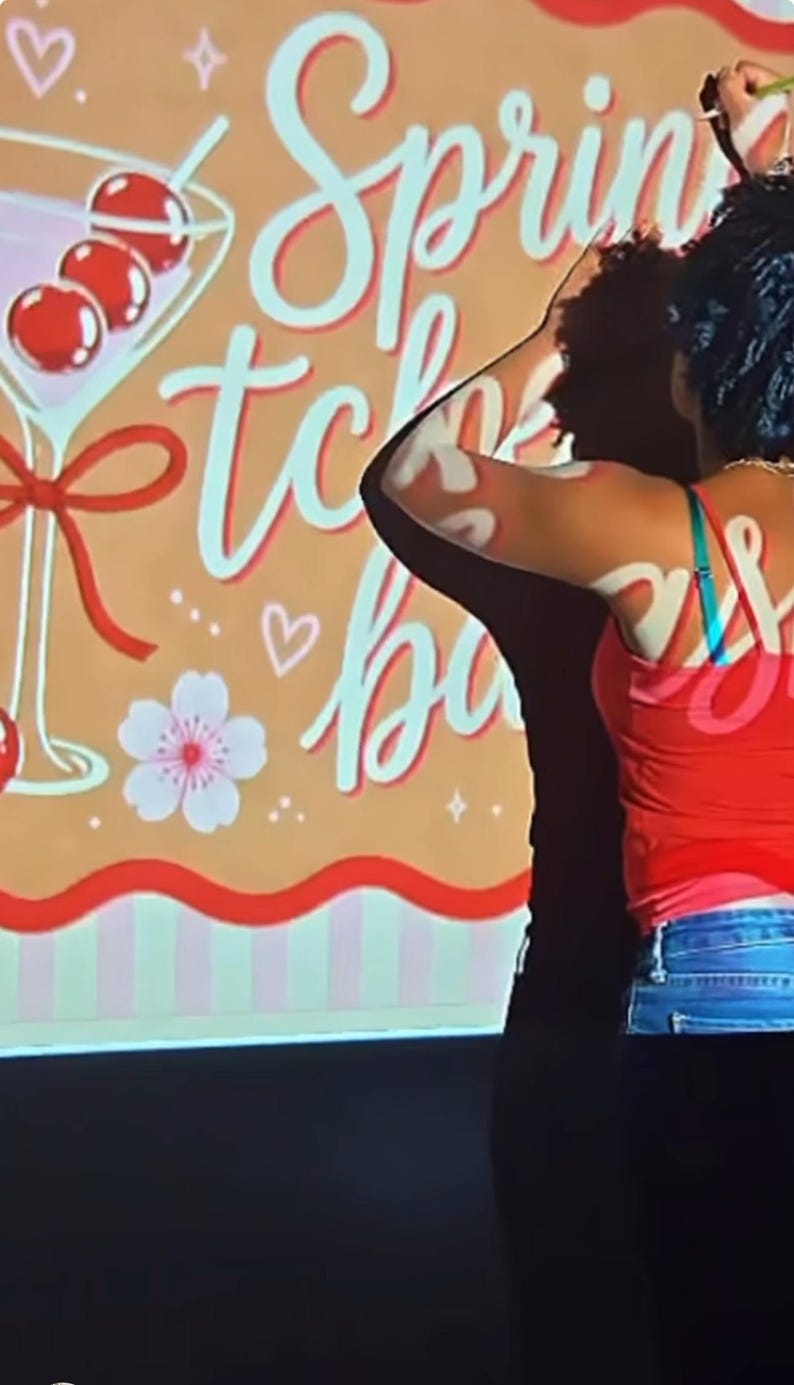 May include: A rectangular sign with a tan background featuring the text Spring tche bas in white script. The design includes a martini glass with three red cherries, a red ribbon, a white flower, and small white heart and star icons.