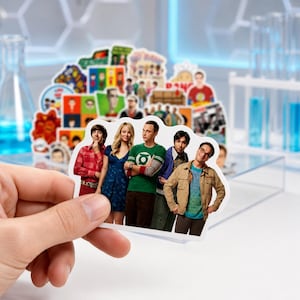 Peut inclure: Un autocollant en vinyle découpé représentant un portrait de groupe de cinq personnages de la série télévisée The Big Bang Theory, incluant des personnes en tenue décontractée comme un t-shirt vert avec un logo, une robe bleue et une veste beige.