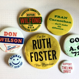May include: Nine vintage political campaign buttons featuring various candidates. The buttons are round and feature colorful designs with text such as "Don Wilson", "Ruth Foster", "Fran Carnochan", and "Go A.C. '72".