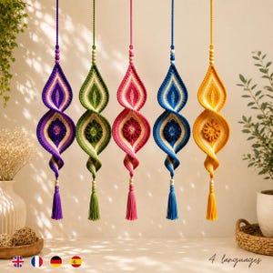 Könnte beinhalten: Fünf hängende Häkelornamente in Violett, Grün, Pink, Blau und Gelb. Jedes Stück zeigt ein spiralförmiges, tropfenförmiges Design mit einem zentralen Blumenmotiv, Holzperlen an der Aufhängung und einer passenden Quaste am unteren Ende.