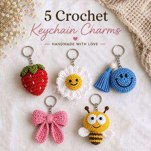 May include: Five crochet keychain charms featuring a red strawberry, a white daisy with a yellow center, a blue smiley face with a tassel, a pink bow, and a yellow and brown bee. The text 5 Crochet Keychain Charms HANDMADE WITH LOVE is visible.