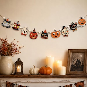 May include: A Halloween-themed garland featuring a string of white wooden beads interspersed with various flat, painted wooden cutouts including a bat, owl, ghost, jack-o'-lanterns, a black cat, and a moon face, all displaying festive orange, black, and white colors.