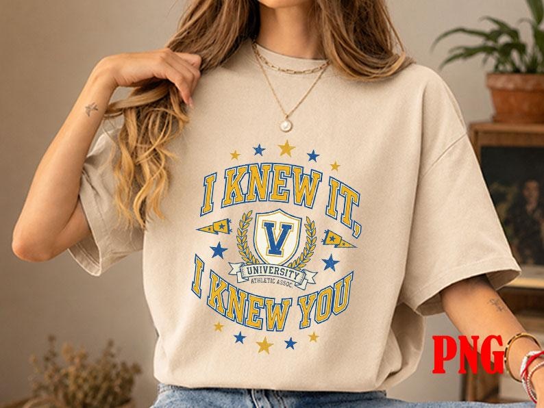 May include: A beige short-sleeve t-shirt featuring a blue and yellow graphic print. The design includes the text I KNEW IT, I KNEW YOU, a central shield with the letter V, and the words UNIVERSITY ATHLETIC ASSOC, surrounded by small stars.
