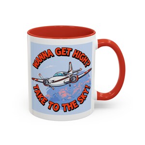 May include: A white ceramic mug with a bright red interior and handle. The exterior features a cartoon illustration of a small airplane flying through blue clouds with the orange text WANNA GET HIGH? TAKE TO THE SKY! printed in a circular arc.