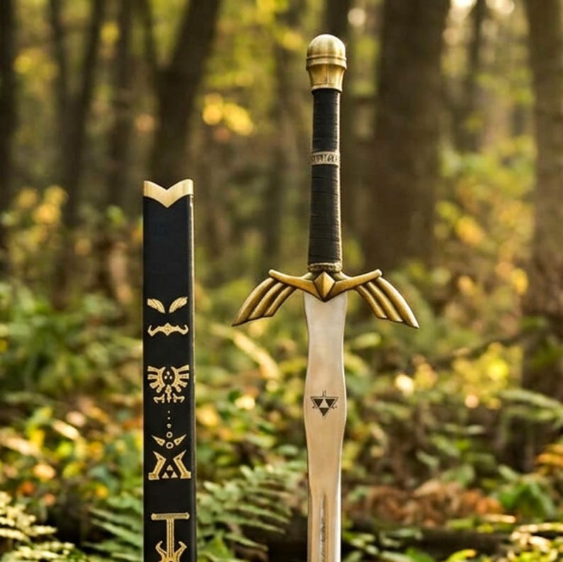 May include: A metal sword with a black wrapped handle, a gold-colored pommel, and a gold-colored crossguard shaped like wings. The blade features a black triangular triforce symbol. Beside it stands a black scabbard with gold-colored etched symbols.