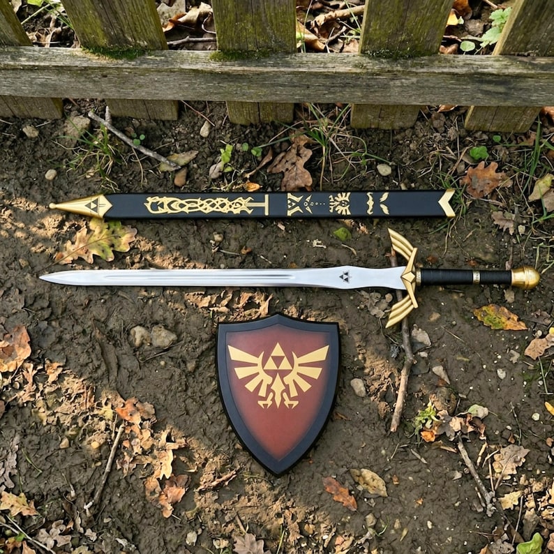 May include: A silver-colored sword with a black handle and gold-colored crossguard, a black scabbard featuring gold-colored decorative patterns, and a shield with a brown center and a gold-colored emblem featuring a bird and a triangle.