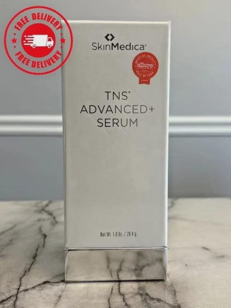 Op de afbeelding: Een witte rechthoekige doos van SkinMedica TNS Advanced+ Serum met zwarte tekst, een zilveren basis en een rood Allure Best of Beauty Hall of Fame-zegel. De verpakking toont het nettogewicht van 1,0 oz / 28,4 g op het onderste deel van de voorzijde.