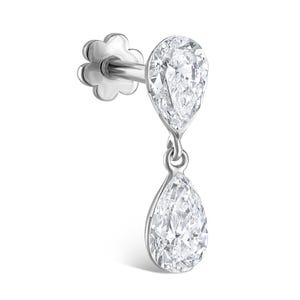 May include: A silver-toned stud earring featuring two pear-shaped clear stones. The upper stone is fixed to the post, while the lower pear-shaped stone hangs freely from a small jump ring. The earring includes a flower-shaped screw-back closure.