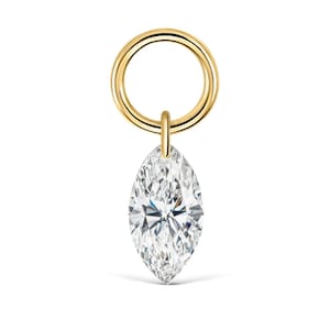 Può includere: Un ciondolo ad anellino in oro con una singola pietra preziosa trasparente a taglio marquise. L'anello in metallo dorato lucido è circolare e la pietra bianca sfaccettata è sospesa a una piccola contromaglia verticale in oro.