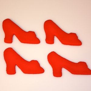 May include: Four red high-heeled shoes, all facing the same direction, are arranged in a symmetrical pattern on a white background.