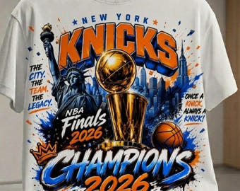 Puede incluir: Una camiseta blanca con un estampado gráfico de los New York Knicks, la Estatua de la Libertad, un trofeo de baloncesto y un balón. El texto incluye "NEW YORK KNICKS", "THE CITY. THE TEAM. THE LEGACY.", "NBA Finals 2026", "CHAMPIONS 2026" y "ONE TEAM. ONE CITY. ONE GOAL."