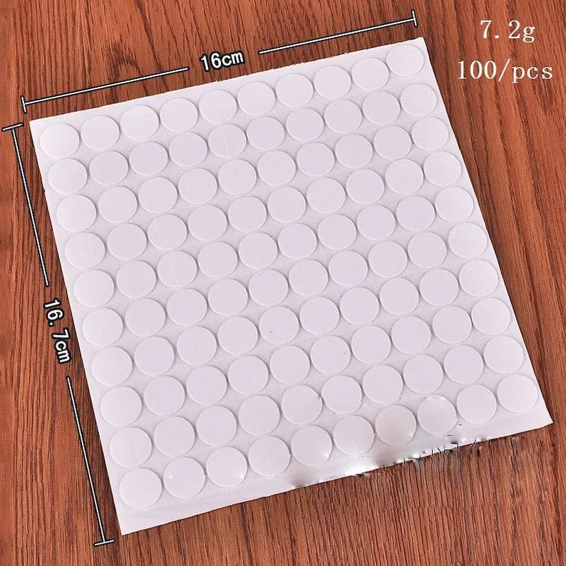 May include: A square sheet of 100 white circular adhesive stickers arranged in a grid. The sheet measures 16 cm by 16.7 cm, with a total weight of 7.2g. Each sticker is a solid white circle, presented as a set of 100 pieces on a single backing sheet.