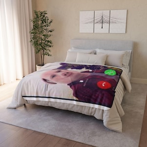 Può includere: Una coperta rettangolare con una grande stampa ad alta risoluzione di un maiale che indossa una camicia a quadri rosso scuro. L'immagine imita la schermata di una chiamata in arrivo su smartphone, con un tasto verde di risposta e uno rosso.