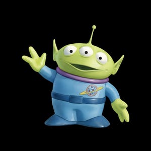 May include: A three-eyed green alien figurine with pointed ears and a single antenna on its head. The character wears a blue space suit with a purple collar, a blue belt, and a circular planet emblem on the chest, with one hand raised in a wave.