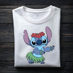 May include: A white crew neck t-shirt featuring a graphic print of the blue character Stitch wearing a red flower crown and a green hula skirt. The character is depicted in a dancing pose with arms extended. The shirt has a simple round neckline.