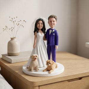 以下が含まれることがあります： ウェディングドレスとベールを身にまとった花嫁と、紫色のスーツを着た花婿のカスタムボブルヘッドフィギュアセット。クリーム色と薄茶色の2匹の小さな犬のフィギュアが、円形の白い台座の上で足元に座っています。